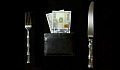 a table setting with a knife and fork and a wallet full of money where the plate usually would be